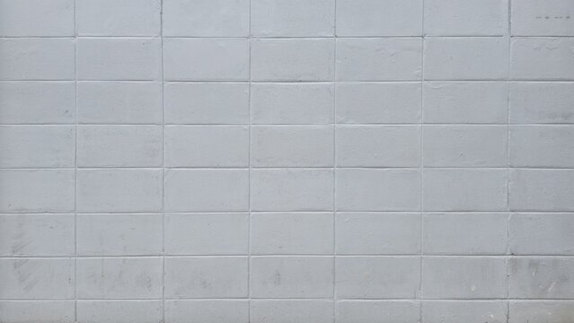 Grey concrete block wall texture background. Grid pattern of a painted grey cinder block wall with rough surface. Grey cement brick pattern texture surface.