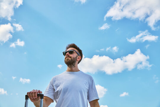 Low Angle View of Happy Man with Suitcase Against Blue Sky