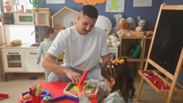 Man reaches hand to help girl arrange wooden puzzle pieces on colorful table in playroom building; nurturing calm.