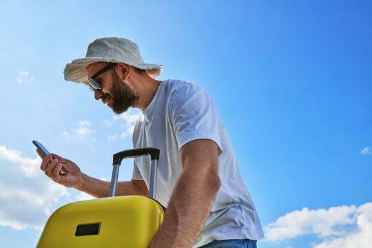 Traveler Man Using Smartphone Holding Yellow Suitcase Outdoors