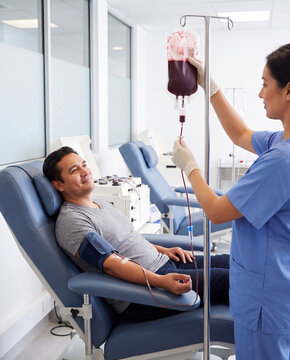 Nurse checking a blood bag beside a donor reclining in a donation chair