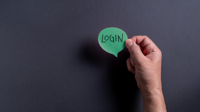 Hand holding green paper speech bubble with the word login in a dark setting