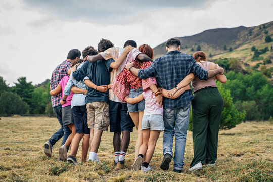 Multicultural group walking together with arms around each other in nature, symbol of social cohesion and belonging