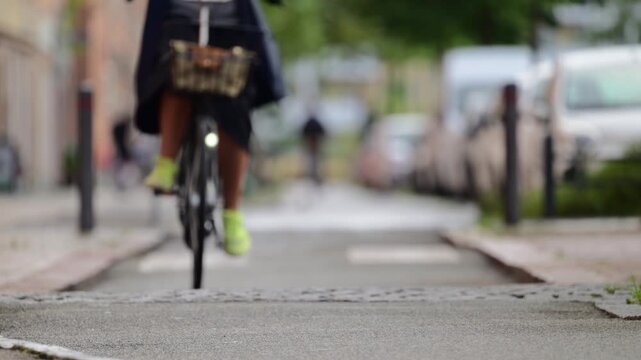 A blurred ground level shot shows two cyclists riding on a paved path in an urban area, highlighting movement and outdoor activity.