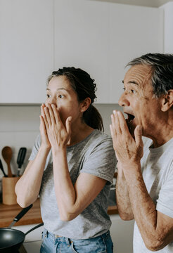 Shock and surprise concept, mature couple reacting with disbelief and amazement in a home kitchen, unexpected news or sudden realization for seniors