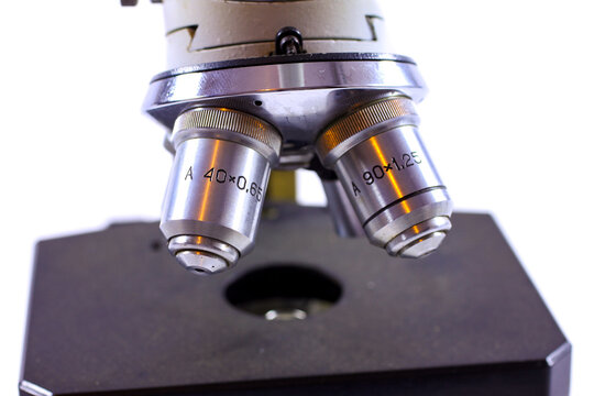 Close-up view of vintage microscope objective lenses above the stage, showing 40x and 90x magnification markings and detailed metal optics.