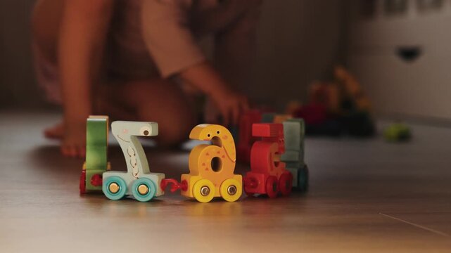 Unrecognizable child playing with a colorful number train toy during indoor play at home.