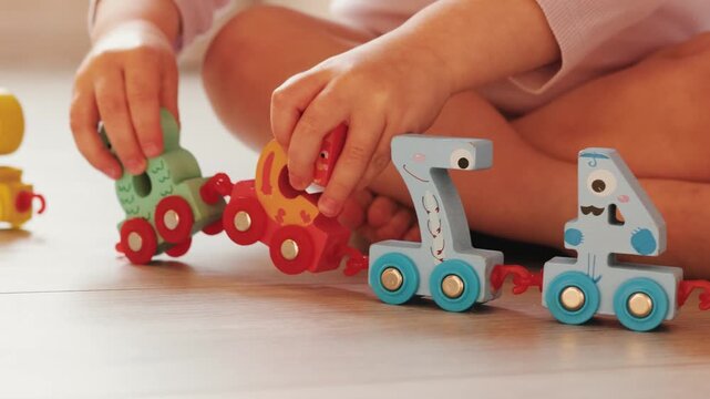 Unrecognizable child explores a colorful number train toy, learning numbers through play.
