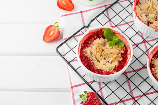 Rhubarb and strawberry crumble in a baking form on a white wooden background. Top view