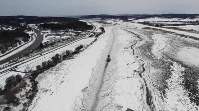 Icebreaker ship navigating frozen Gota alv river near Alvangen, Sweden in winter, aerial panoramic pullback