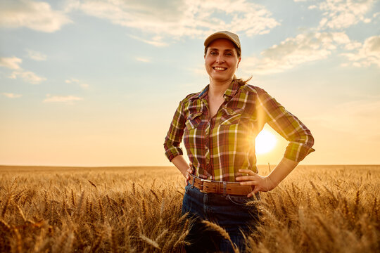 Female farmer standing proud in golden wheat field during sunset, embracing agriculture