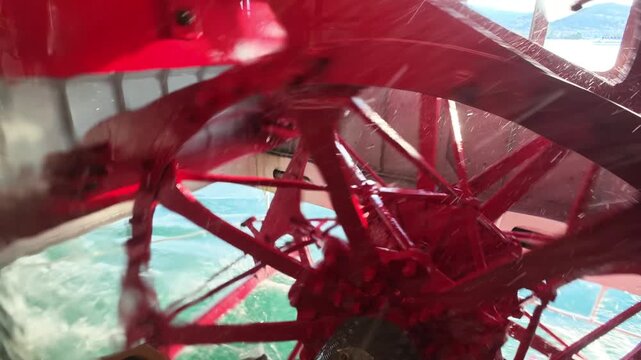 Red paddle wheel spinning and propelling the historic steamboat - PS Gallia, a beautifully restored 1902 steam paddle wheeler, on Lake Lucerne, Switzerland, Europe.