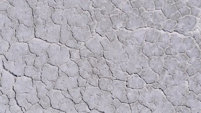 Dynamic aerial drone footage over the Great Salt Flats, beginning with a top-down view of the textured salt landscape before smoothly tilting upward to reveal the vast horizon and expansive desert sce
