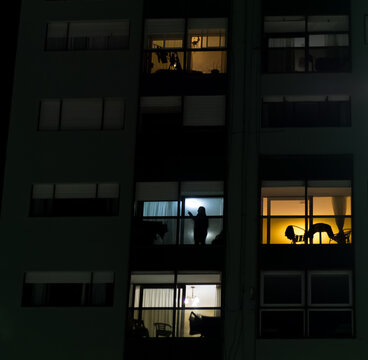 Silhouettes and Illuminated Windows in a Residential Building at Night