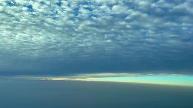 Immersive cockpit view taken from a jet airplane while flying at sunrise between layes of etheral clouds, with a blue color sky at the back.