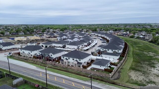 Suburban townhomes border Mansfield Webb Road opposite Yardly Eden development tract. Shingle roofs, brick perimeter walls, marked traffic lanes showcase housing expansion, Arlington, Texas