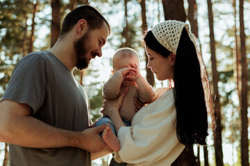 Fototapeta premium Happy family enjoying time in a forest with their baby