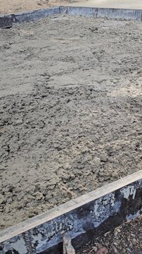 Construction of a concrete slab in a backyard area showing the mixing and pouring process