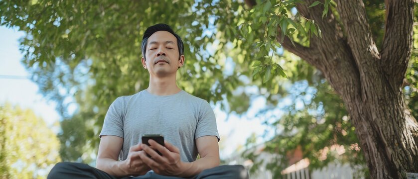 Person meditating outdoors under a tree.