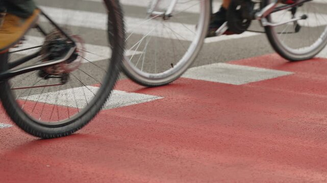 Close-up multiple cyclists traveling on red designated bike lane through modern urban environment, clear road markings, separated cycling infrastructure, active mobility and sustainable city transport