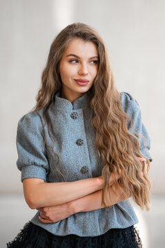 Young woman with long wavy hair wearing grey buttoned coat looking to side, with woman, portrait, hair, wavy detail, showing longhair, brownhair, coat, greycoat context