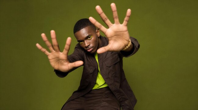 Young Black Man With Neon Makeup Reaching Hands Forward