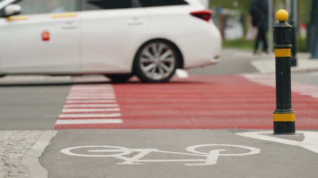 Bicycle lane symbol painted on asphalt at modern urban intersection, with cars and city traffic in background, cycling infrastructure, road markings and sustainable transportation