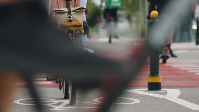 Cyclists riding along designated urban bike lane with prominent bicycle road markings and red pavement at crossing, modern cycling infrastructure, active mobility and sustainable transportation