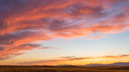 Obraz premium Vibrant pink and orange clouds light up the sunset sky over a peaceful prairie landscape
