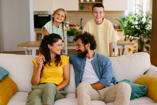Happy parents posing with their children at home on the sofa