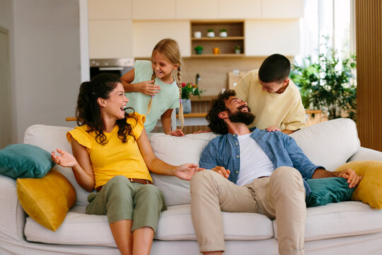 Parents enjoying a playful moment with their children on the sofa