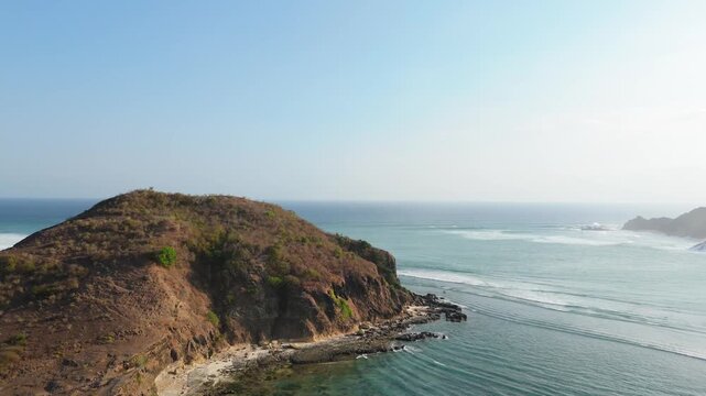 Aerial view of rocky point and offshore reef break beside coastal hill in south Lombok Indonesia