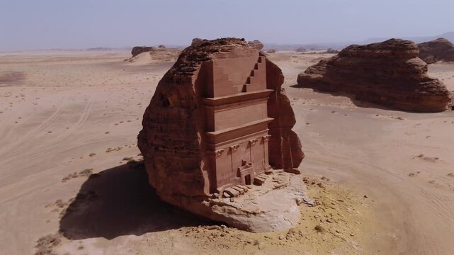 Aerial drone orbiting shot of Qasr Al-Farid monolithic Nabataean rock-cut tomb in Hegra, AlUla, Saudi Arabia