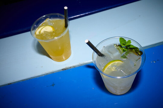 Two soft drinks in plastic cups on a blue table.