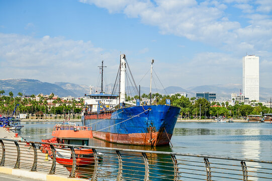 Blue cargo ship docked in the port of Mersin against the city skyline; freighter and work vessel at the pier; Mersin Province, Mediterranean coast, southern Turkey 13.9.2025