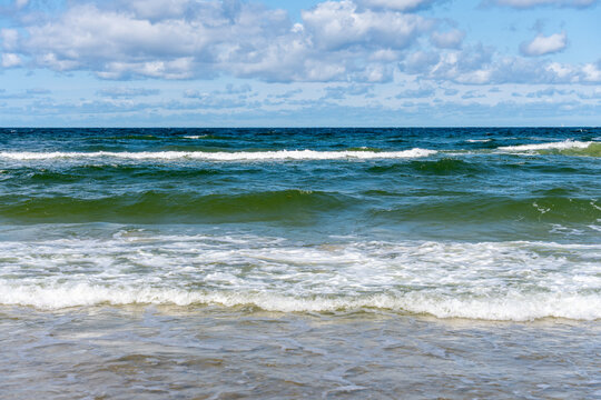 Sea Waves Rolling Toward Sandy Beach Under Cloudy Blue Sky Summer Coastal Nature Background