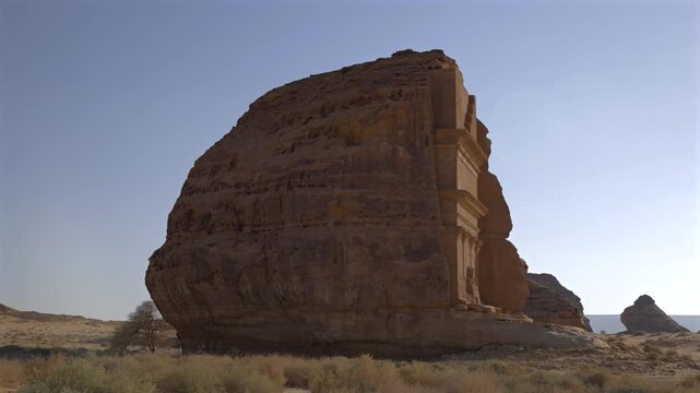 Cinematic wide shot of majestic Qasr Al-Farid monolithic rock carved tomb standing tall in peaceful morning sunlight in Madain Saleh Hegra AlUla