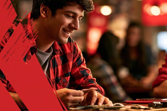 Young man wearing red plaid shirt playing card game with friends at indoor social gathering venue