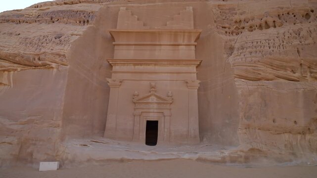 Slow push-in shot of ancient Nabataean rock-cut tomb facade in Hegra, AlUla