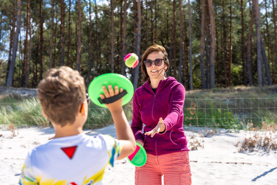 Woman And Child Playing Paddle Ball On Sandy Beach During Summer Family Outdoor Recreation