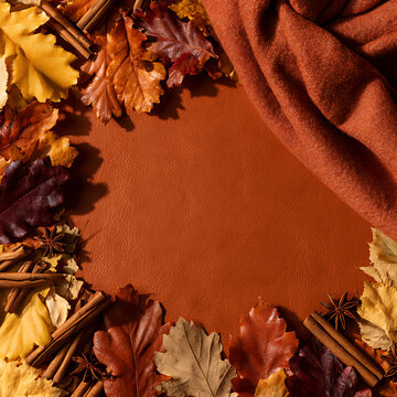 Autumn leaves and spices arranged on a brown leather surface in a cozy setup