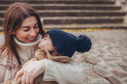 Loving mother embracing her daughter outdoors in autumn. Maternal love, family bonding, childhood happiness, cozy autumn vibes.