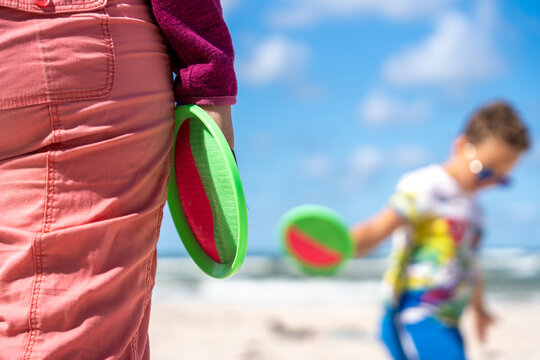 Woman And Child With Paddle Ball Game On Beach During Summer Family Vacation And Play