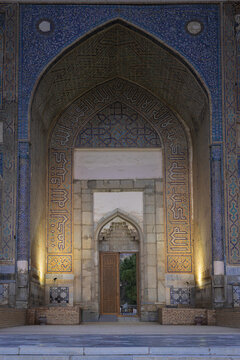 Bibi-Khanym Mosque entrance portal with intricate mosaic tilework and pointed arch illuminated at dusk in Samarkand. Ideal for travel publications, cultural heritage materials, and architectural.