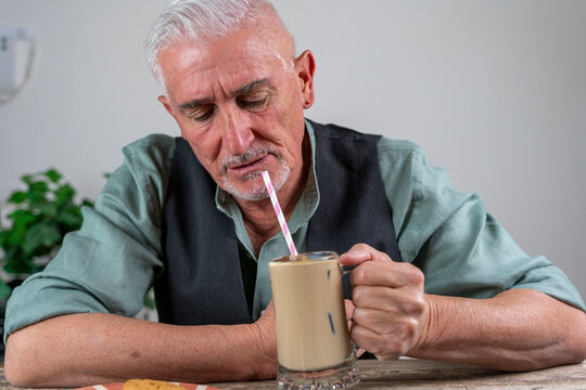 Senior man enjoying an iced coffee through a straw, finding refreshment