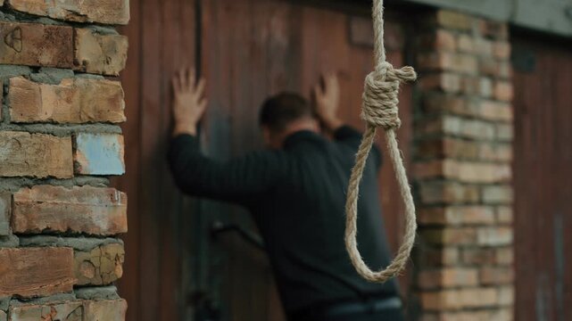 A nervous man on the background of a rope with a noose for suicide. A man on the verge of death. Suicide by hanging. Human psychology. Nervous breakdown.
