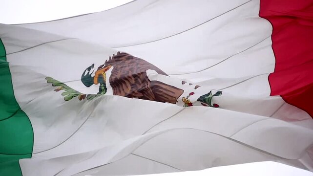 Mexican flag waving in the wind, showcasing the national coat of arms with eagle and snake, symbolizing Mexico, national identity, patriotism, heritage and cultural pride.