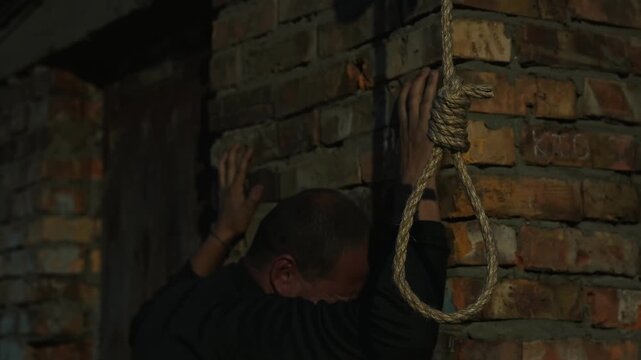 A nervous man on the background of a rope with a noose for suicide. A man on the verge of death. Suicide by hanging. Human psychology. Nervous breakdown.