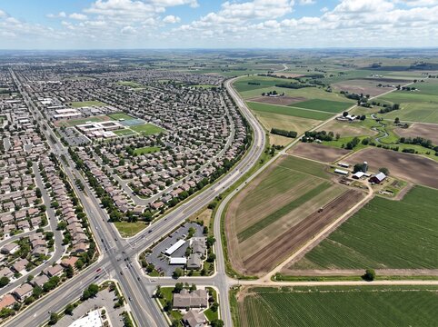 Aerial view of suburban neighborhood boundary meeting expansive agricultural farmland and rural countryside fields