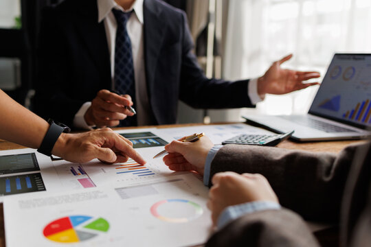 Business professionals analyzing financial data, discussing market strategy, and collaborating on reports during an office meeting, planning future growth